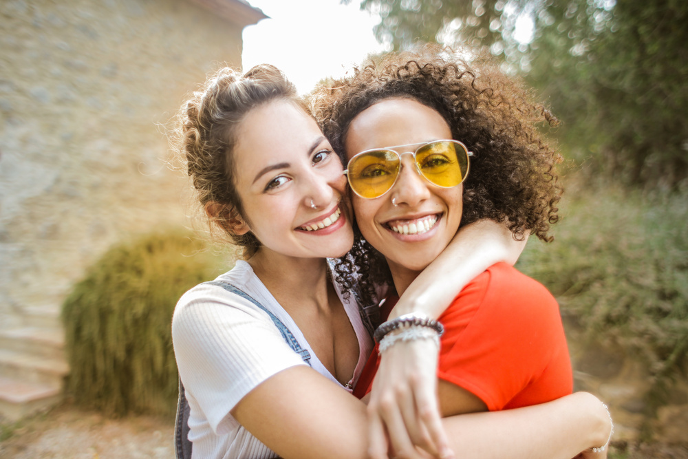 Selective Focus Portrait Photo of Two Smiling Women Hugging Each Other